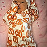 Cecilia is registered to the contest to win money with this photo: baby, infant, onesie, pretzel_pattern, clothing, hat, blanket, pink, dots, face, hand, lying_down, cute, newborn, person, soft_texture, warm, indoors, portrait, sleepwear