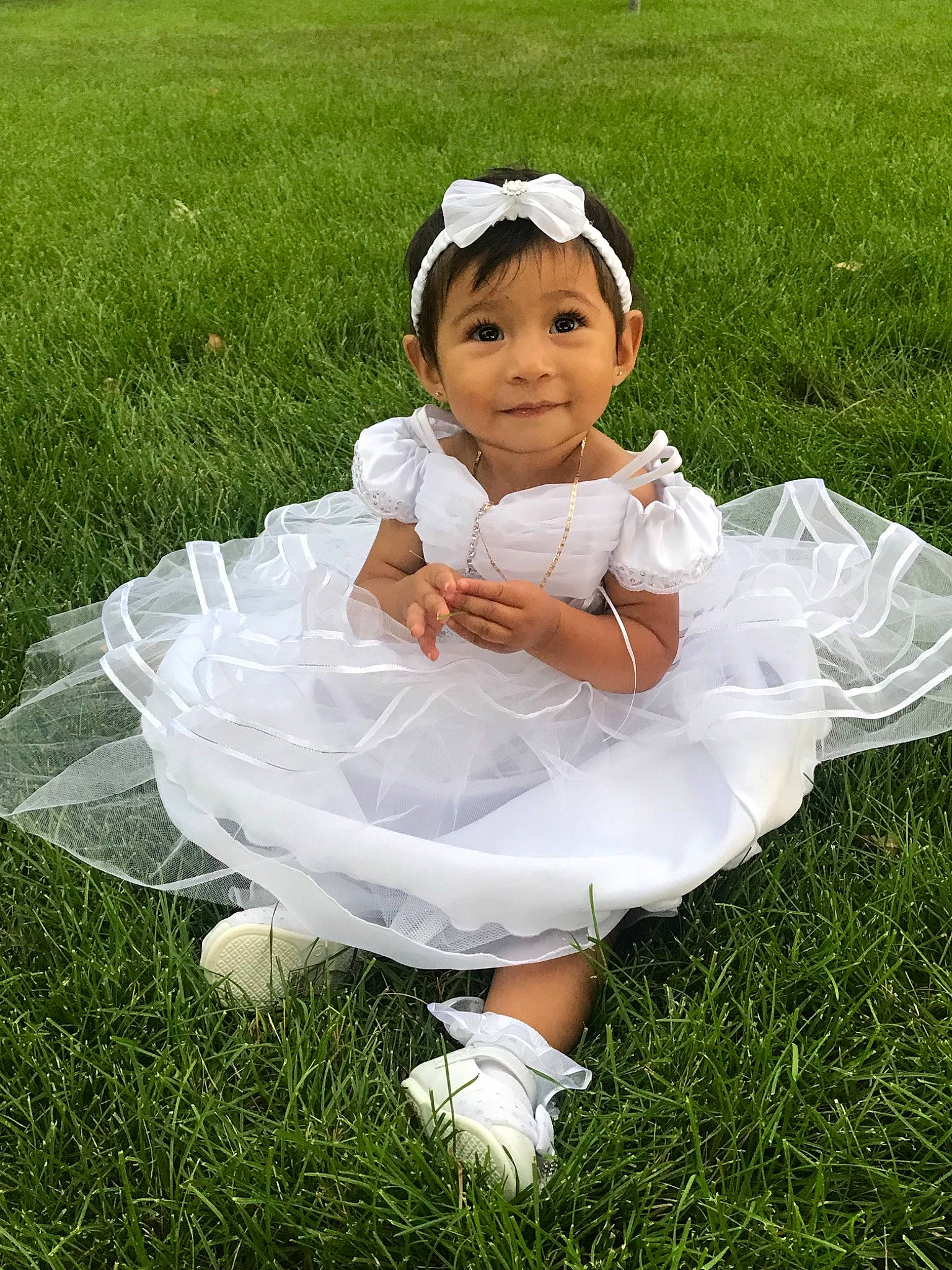 Vivianna is registered to the contest to win money with this photo: baby, baby_toddler_clothing, bridal_accessory, ceremony, child, costume, dress, flower_girl, grass, hair_accessory, happy, headgear, headpiece, headwear, person, plant, ritual, skin, smile, toddler