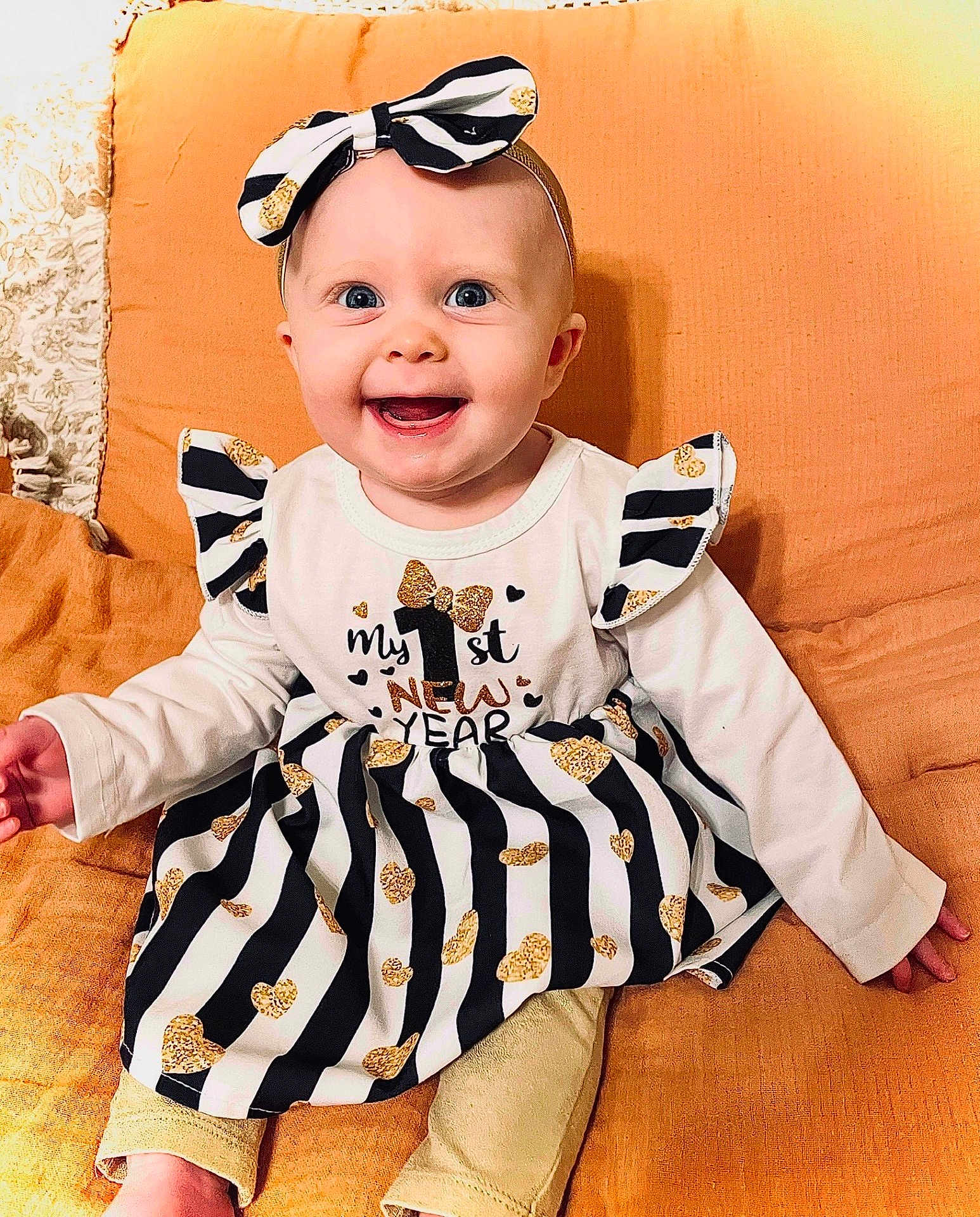 Anna joined the competition — help win amazing prizes! baby, child, smiling, blue_eyes, headband, bow, dress, striped, gold_hearts, sitting, cushion, orange, happy, new_year, celebration, cute, clothing, infant, portrait, indoors