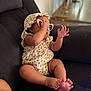 Anyla is registered to the contest to win money with this photo: baby, child, sunglasses, floral_clothing, hat, couch, indoor, furniture, foot, hand, skin, playful, infant, person, casual, comfortable, home, relaxed, seated, adorable