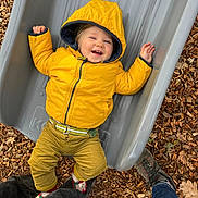 Jules participe au concours pour gagner de l'argent avec cette photo : toddler, child, yellow_jacket, hood, slide, playground, wood_chips, smile, happy, outdoor, pants, belt, socks, shoes, legs, joyful, casual, person, fun, play