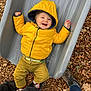 toddler, child, yellow_jacket, hood, slide, playground, wood_chips, smile, happy, outdoor, pants, belt, socks, shoes, legs, joyful, casual, person, fun, play