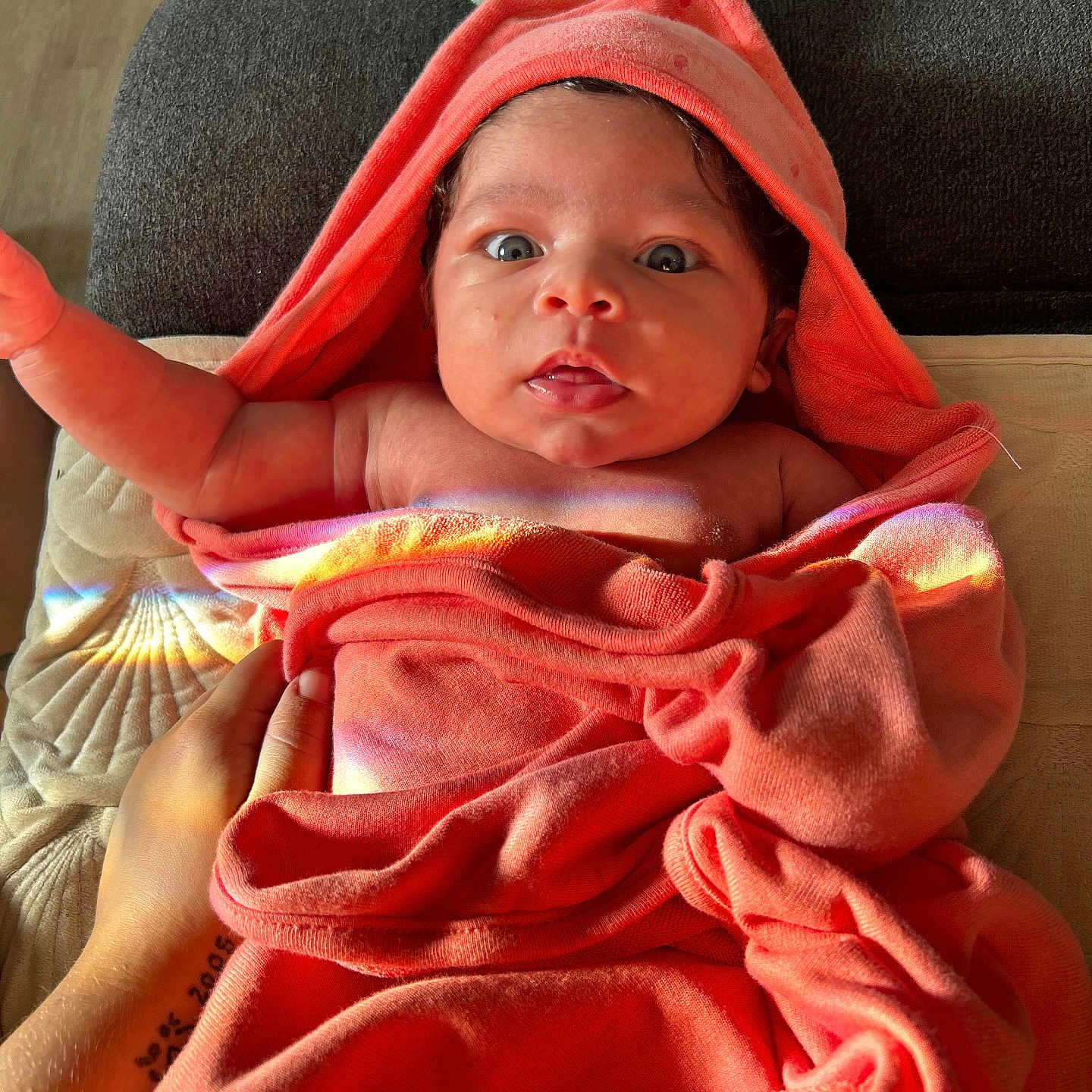 Naylani joined the competition — help win amazing prizes! baby, blanket, couch, cute, expression, fabric, face, hand, hooded_towel, indoor, infant, light, newborn, orange, portrait, rainbow_reflection, skin, tattoo, towel, wide_eyes