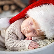 Sarah joined the competition — help win amazing prizes! baby, sleeping, santa_hat, knitted_sweater, blanket, cozy, holiday, christmas, infant, soft_texture, closeup, peaceful, cute, child, portrait, resting, warm, fuzzy, holiday_decor, indoors