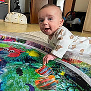 Basil participe au concours pour gagner de l'argent avec cette photo : baby, infant, tummy_time, play_mat, water_play_mat, smiling, hand, face, eyes, onesie, croissant_pattern, indoor, carpet, car_seat, stroller, toy, colorful, floor, mirror, home