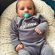 Maylan participe au concours pour gagner de l'argent avec cette photo : baby, infant, pacifier, gray_clothing, cushion, star_pattern, face, hand, cozy, indoor, cute, child, soft_texture, sitting, portrait, comfort, resting, newborn, apparel, home