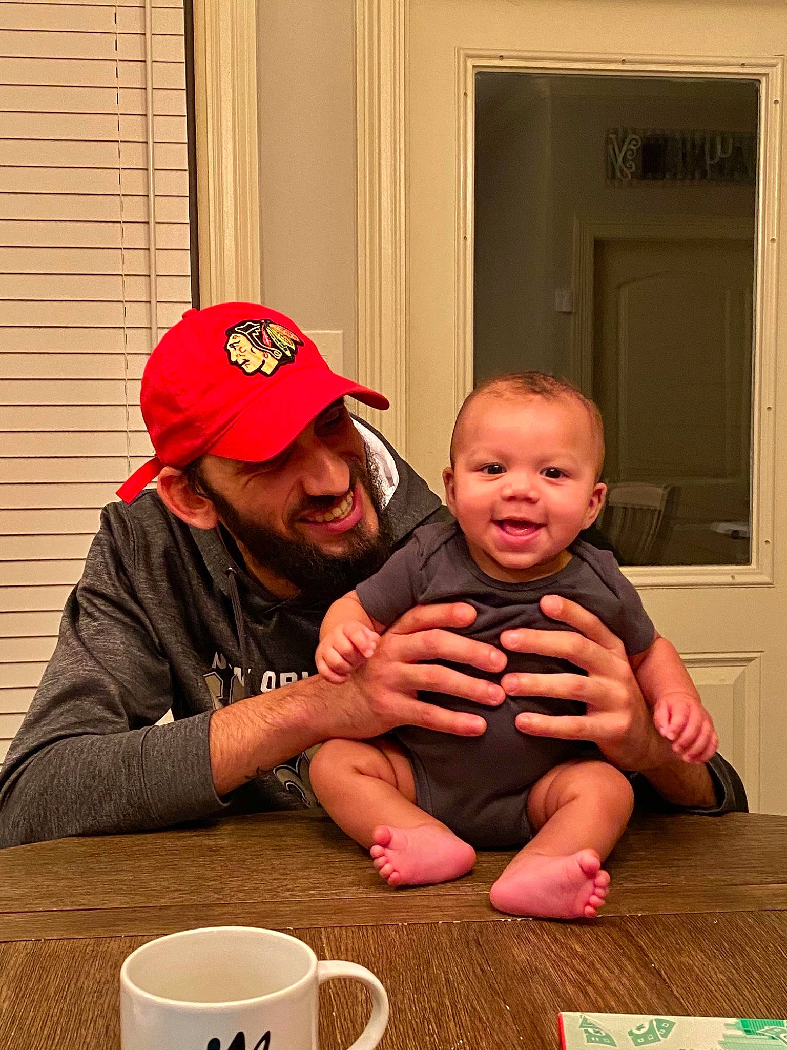 Taylen is registered to the contest to win money with this photo: baby, baby_toddler_clothing, baseball_cap, cap, coffee_cup, cup, door, drinkware, eye, headwear, holiday, human, human_body, joy, mouth, mug, nose, person, red, serveware