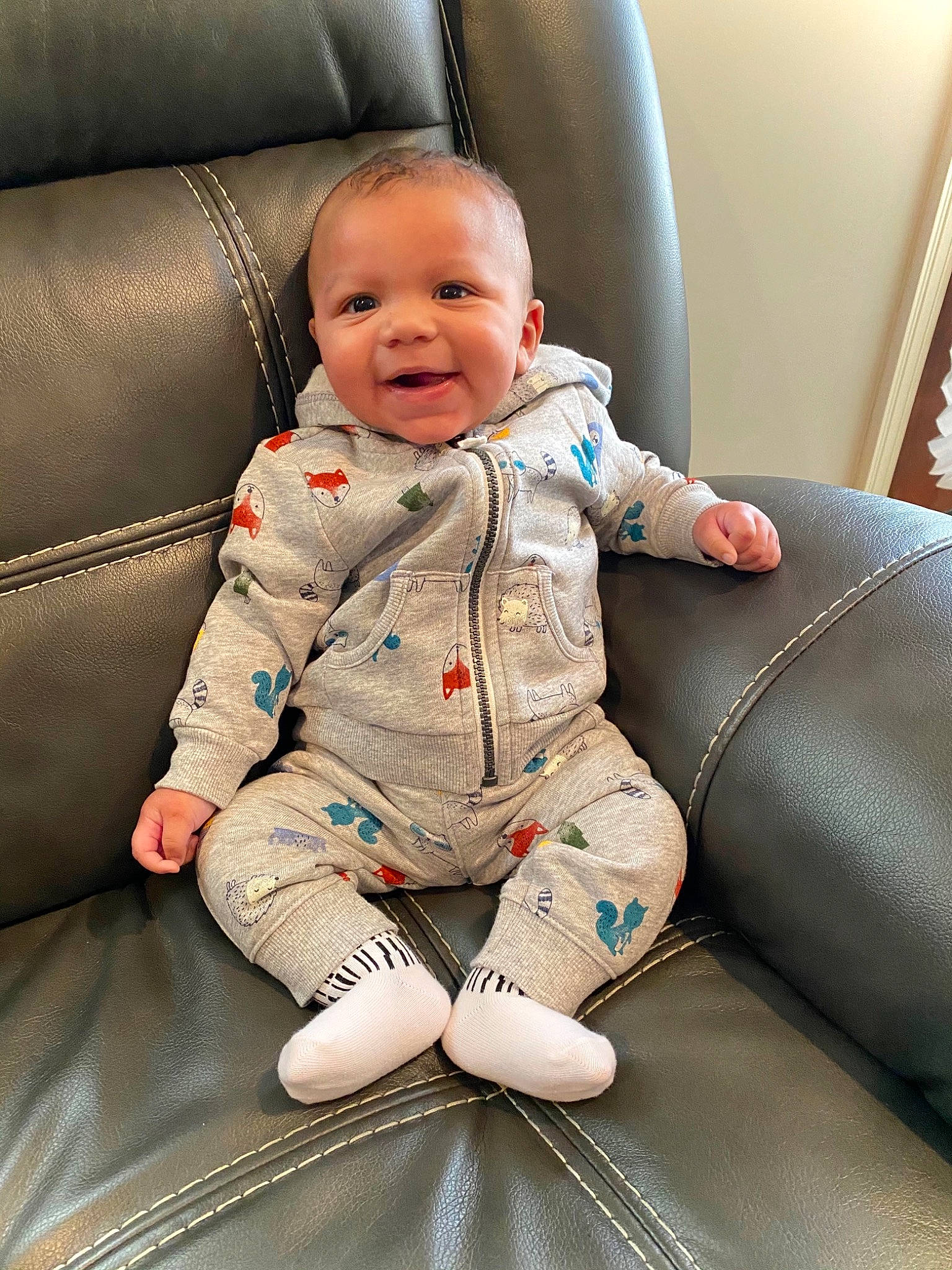Taylen is registered to the contest to win money with this photo: armrest, baby, baby_toddler_clothing, car_seat, cheek, child, comfort, couch, foot, human_body, lap, laugh, leather, living_room, mouth, person, sitting, skin, sleeve, sock