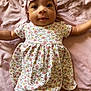 baby, infant, child, pink_bow, headband, floral_dress, blanket, soft_fabric, lying_down, cute, wide_eyes, outstretched_arms, portrait, smiling, happy, indoors, one_person, close_up, skin, face