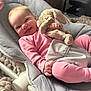 baby, child, pink_clothing, stuffed_animal, bunny, soft_toy, baby_bouncer, cushion, smiling, happy, indoor, blanket, plush, cute, infant, relaxing, person, cozy, face, hand