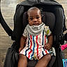 Makaio is registered to the contest to win money with this photo: baby, bib, black_car_seat, calm_expression, car_seat, casual_clothing, child, cute, floor, footwear_absent, home, indoor, infant, looking_at_camera, person, portrait, seated, striped_clothing, toy, wooden_floor