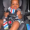 baby, child, car_seat, harness, safety, colorful_clothing, striped_outfit, infant, seat_belt, hand, face, serious_expression, indoor, closeup, person, young_child, protective_gear, baby_seat, seat, snack