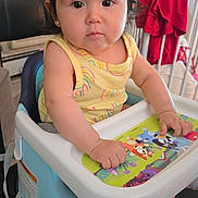 Luxana joined the competition — help win amazing prizes! baby, child, high_chair, yellow_clothing, rainbow_pattern, indoor, furniture, tray, hand, face, curious, black_hair, crib, red_clothing, carpet, earrings, window, home, person, seated