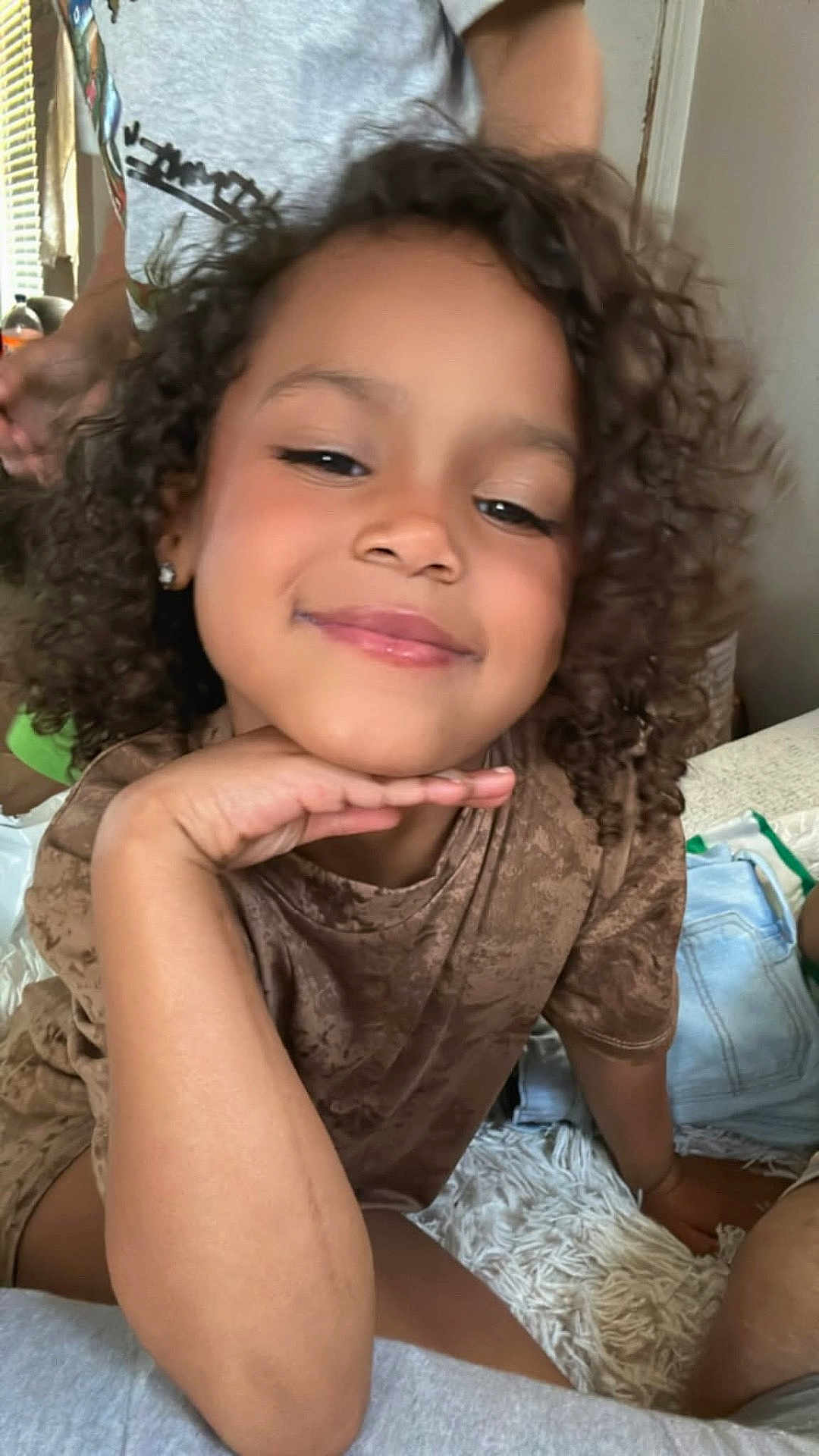 Truu joined the competition — help win amazing prizes! child, curly_hair, smile, indoor, person, face, hand, brown_shirt, relaxed, portrait, casual, happy, kid, young, curly, skin, earrings, seated, cozy, home