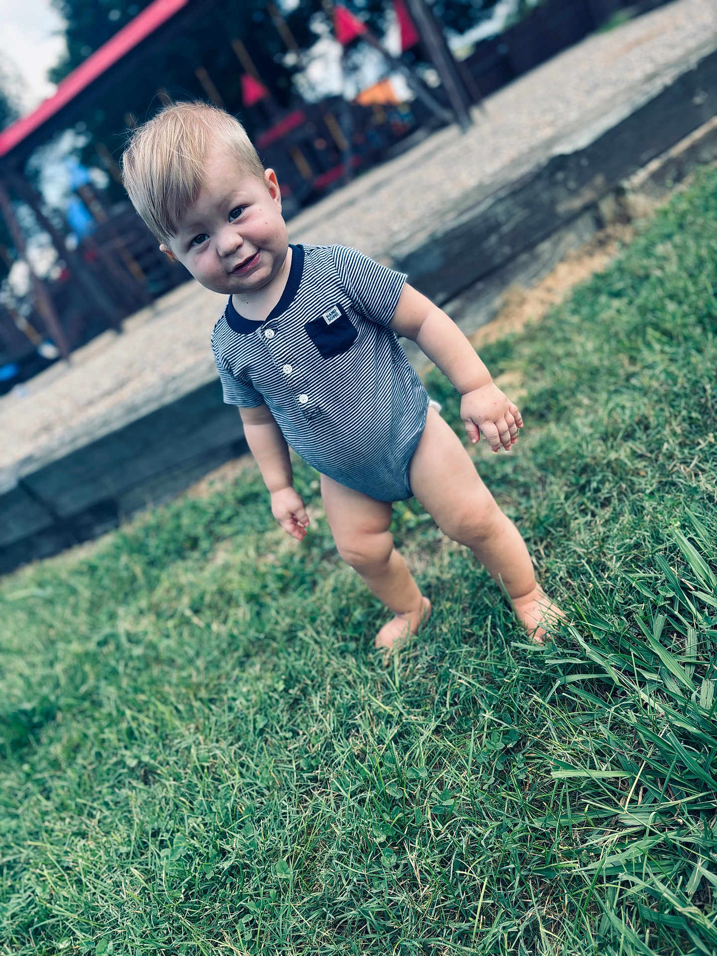 Kayson joined the competition — help win amazing prizes! toddler, child, grass, barefoot, onesie, striped_clothing, outdoor, playground, smile, baby, person, curious, young_child, head, face, short_hair, daylight, nature, fun, candid