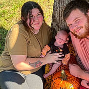 Ellianna is registered to the contest to win money with this photo: family, baby, child, man, woman, tree, grass, pumpkin, tattoo, outdoor, fall, autumn, smile, sleeping, holding, casual_clothing, nature, happy, people, portrait