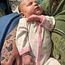 Ellianna is registered to the contest to win money with this photo: baby, sleeping, onesie, pastel_colors, rainbow_pattern, hand, tattoo, butterfly_tattoo, arm, person, indoor, cozy, infant, newborn, clothing, holding, peaceful, cute, resting, closeup