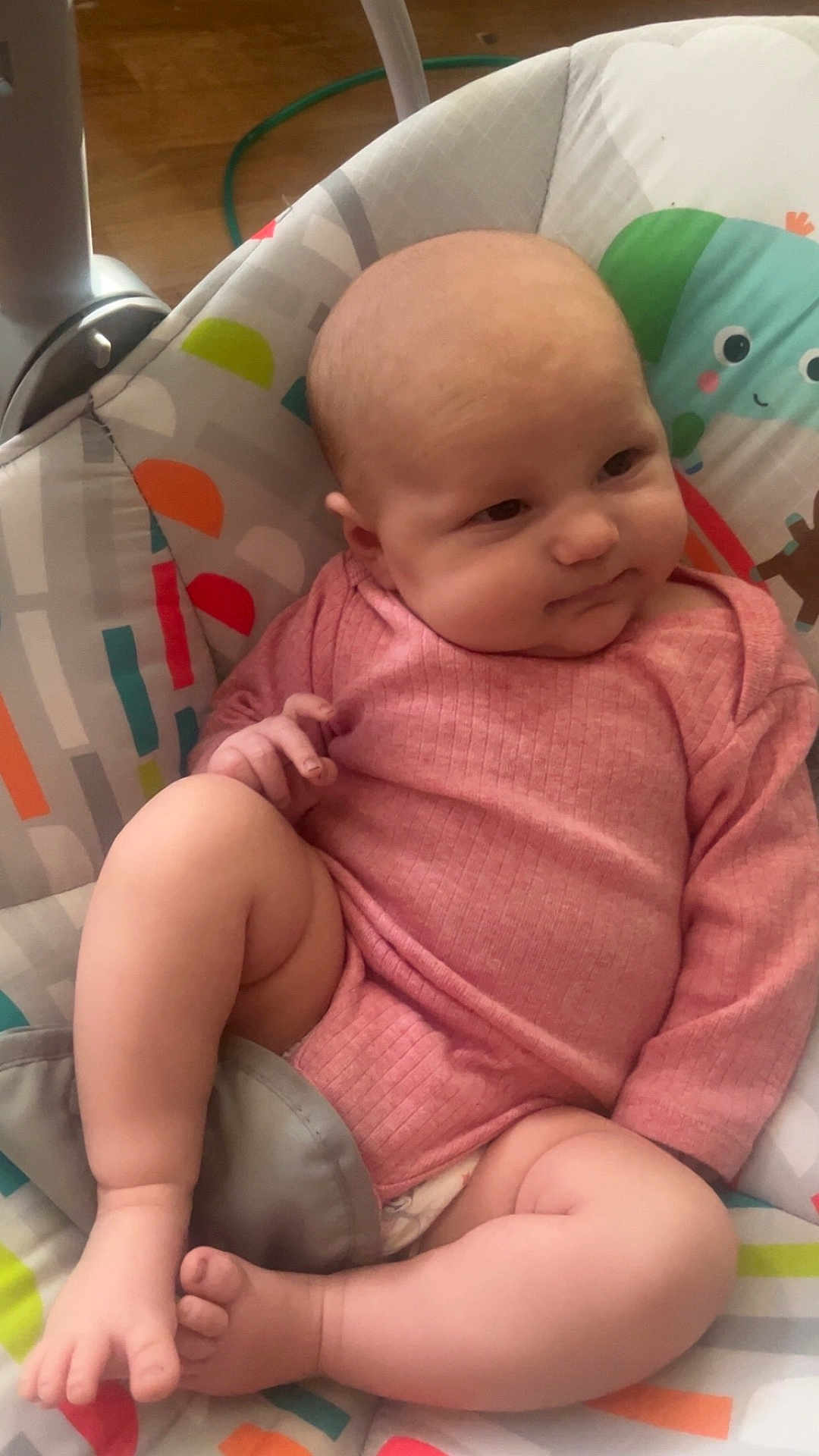 Ellianna joined the competition — help win amazing prizes! baby, infant, pink_clothing, baby_seat, patterned_fabric, legs, feet, hand, face, head, skin, expression, indoor, floor, wooden_floor, cute, child, newborn, comfort, relaxed