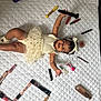 baby, child, infant, smiling, lying_down, white_bedspread, makeup_products, lipstick, brush, cosmetics, headband, dress, tutu, happy, cute, arm_up, legs_bent, skin, beauty, indoor