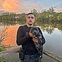 Unik participe au concours pour gagner de l'argent avec cette photo : calm, casual_clothing, clouds, dog, evening, holding, lake, man, nature, outdoor, person, pet, puppy, reflection, scenic, sky, sunset, trees, water, wooden_rail