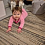 baby, carpet, child, crawling, cute, decor, floor, furniture, holiday_decor, home, indoor, patterned_rug, pink_clothing, reindeer_decoration, rug, santa_figure, smiling, stool, toy, wooden_cabinet