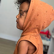 Rylan is registered to the contest to win money with this photo: child, toddler, hood, orange_clothing, curly_hair, profile, indoor, sleeveless, cute, young_child, side_view, soft_lighting, skin, face, person, clothing, portrait, childhood, expression, casual