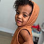 Rylan is registered to the contest to win money with this photo: toddler, child, curly_hair, smile, hooded_vest, orange_clothing, indoor, portrait, cute, happy, face, person, knitted, young_child, playful, looking_back, skin, headwear, casual, warm_colors