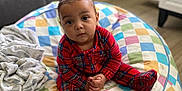 Aislynn is registered to the contest to win money with this photo: toddler, child, baby, plaid, onesie, beanbag, colorful, checkered, hair_buns, indoor, floor, blanket, furniture, cabinet, curious, seated, wooden_floor, cozy, person, portrait