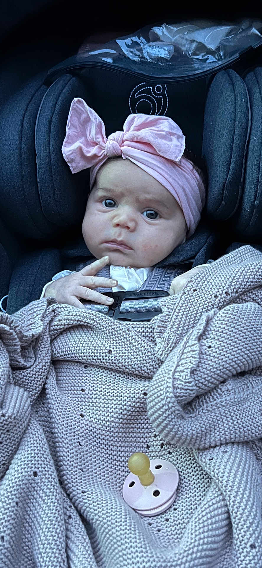 Anya joined the competition — help win amazing prizes! baby, infant, car_seat, blanket, headband, pink, pacifier, knitted, serious_expression, child, toddler, clothing, seatbelt, cute, indoor, portrait, person, baby_accessory, fabric, closeup
