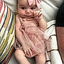 baby, infant, pink_dress, headband, bow, couch, cushions, blanket, striped, hand, legs, face, skin, portrait, indoors, comfortable, cute, child, person, relaxing