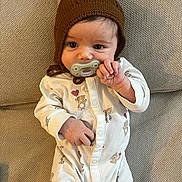 Anya joined the competition — help win amazing prizes! baby, infant, pacifier, brown_hat, onesie, teddy_bear_print, couch, fabric_texture, lying_down, cute, child, small_hand, face, indoors, cozy, comfortable, young_child, sleepwear, knit_hat, portrait