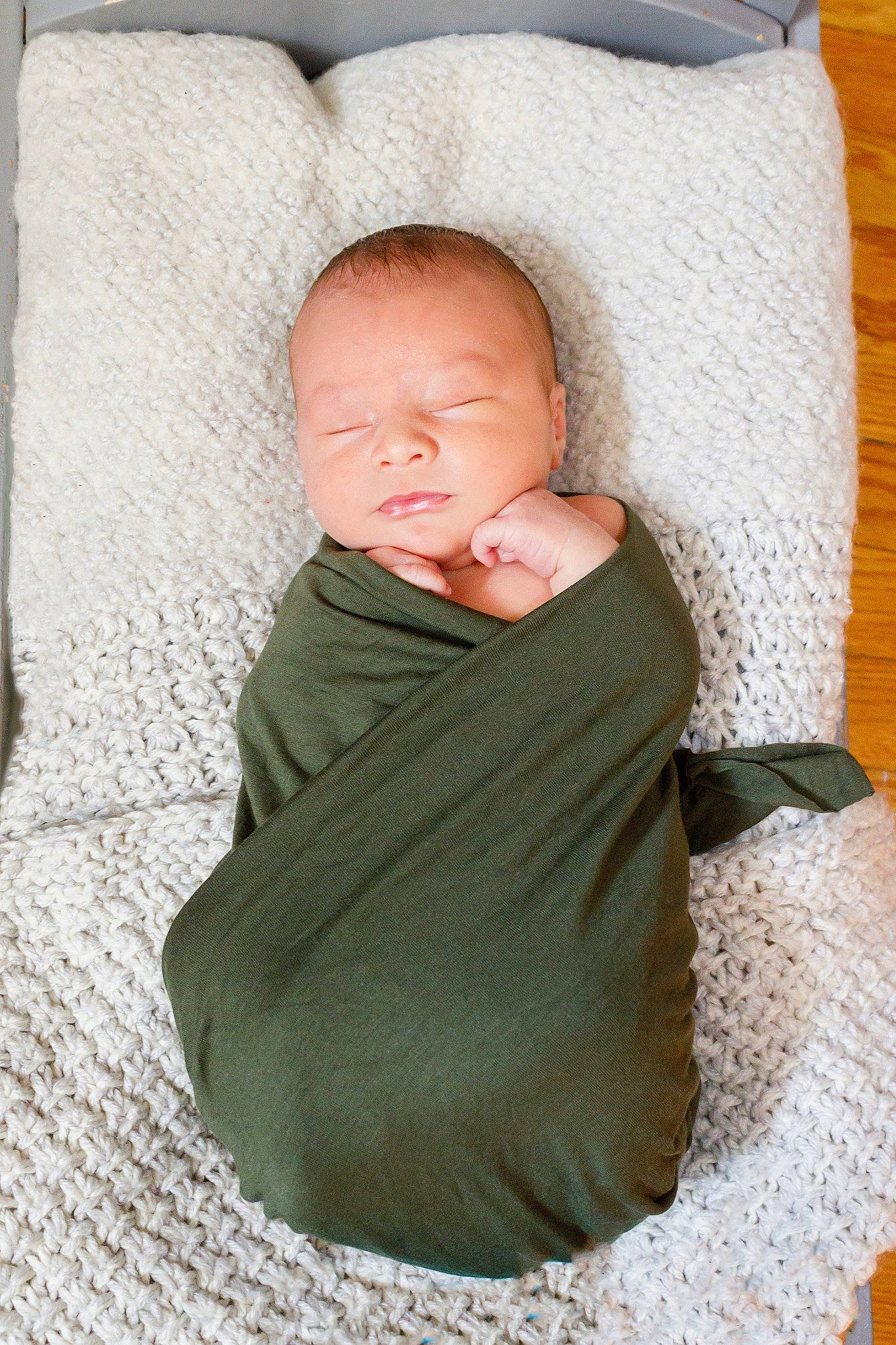 Leonidas is registered to the contest to win money with this photo: baby, baby_products, baby_sleeping, baby_toddler_clothing, bedding, cheek, child, comfort, flooring, headgear, human_body, linens, neck, pattern, person, sitting, sleeve, textile, toddler, wood