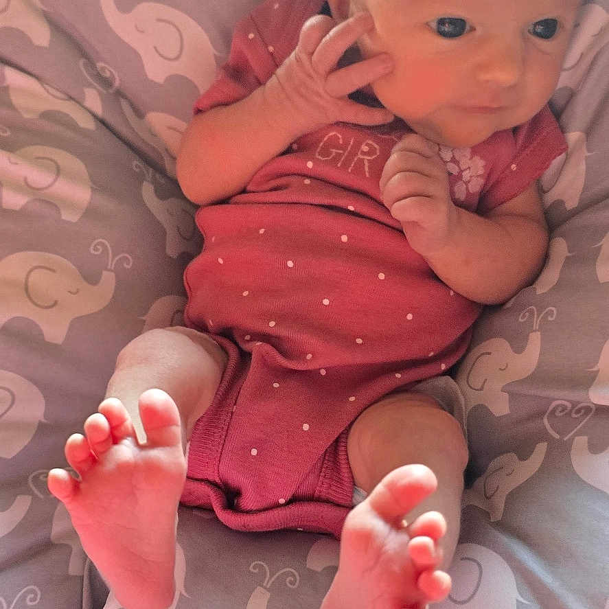 Melody joined the competition — help win amazing prizes! baby, infant, child, portrait, lying_down, sitting, pink_onesie, curious, awake, face, hands, feet, bare_feet, cushion, blanket, elephant_pattern, nursery, indoor, adorable, photograph