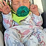 newborn, baby, infant, sleeping, pacifier, car_seat, headwrap, pajamas, blanket, cuddled, portrait, indoors, vehicle, child, face, hands, cozy, floral, striped_pillow, relaxed