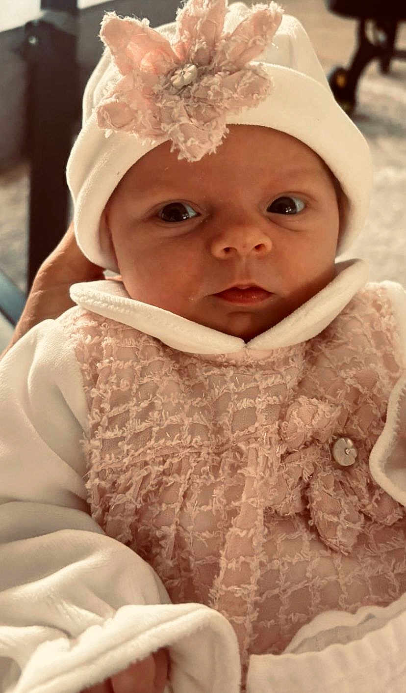 Annie joined the competition — help win amazing prizes! baby, infant, hat, flower, pink, white, clothing, cute, portrait, face, eyes, warm, cozy, closeup, newborn, person, soft, texture, fabric, indoors