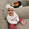 baby, child, smiling, headband, flower, red_roses, striped_pants, couch, indoor, table, box, white_shirt, happy, person, portrait, sitting, cozy, cute, infant, home