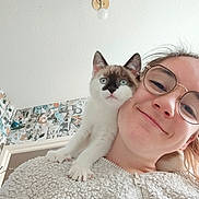 Maurice Dodu a rejoint le concours — aidez-le/la à gagner de superbes lots ! casual, cat, closeup, cute, face, fluffy_jacket, glasses, happy, home, indoor, kitten, light_fixture, patterned_wall, person, pet, portrait, shoulder, smile, white_jacket, young_adult