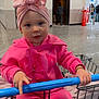 toddler, child, shopping_cart, pink_clothing, headwrap, indoor, store, floor, blue_handle, person, jewelry, bracelet, necklace, expression, curious, clothing, retail, floor_tiles, shopping, casual