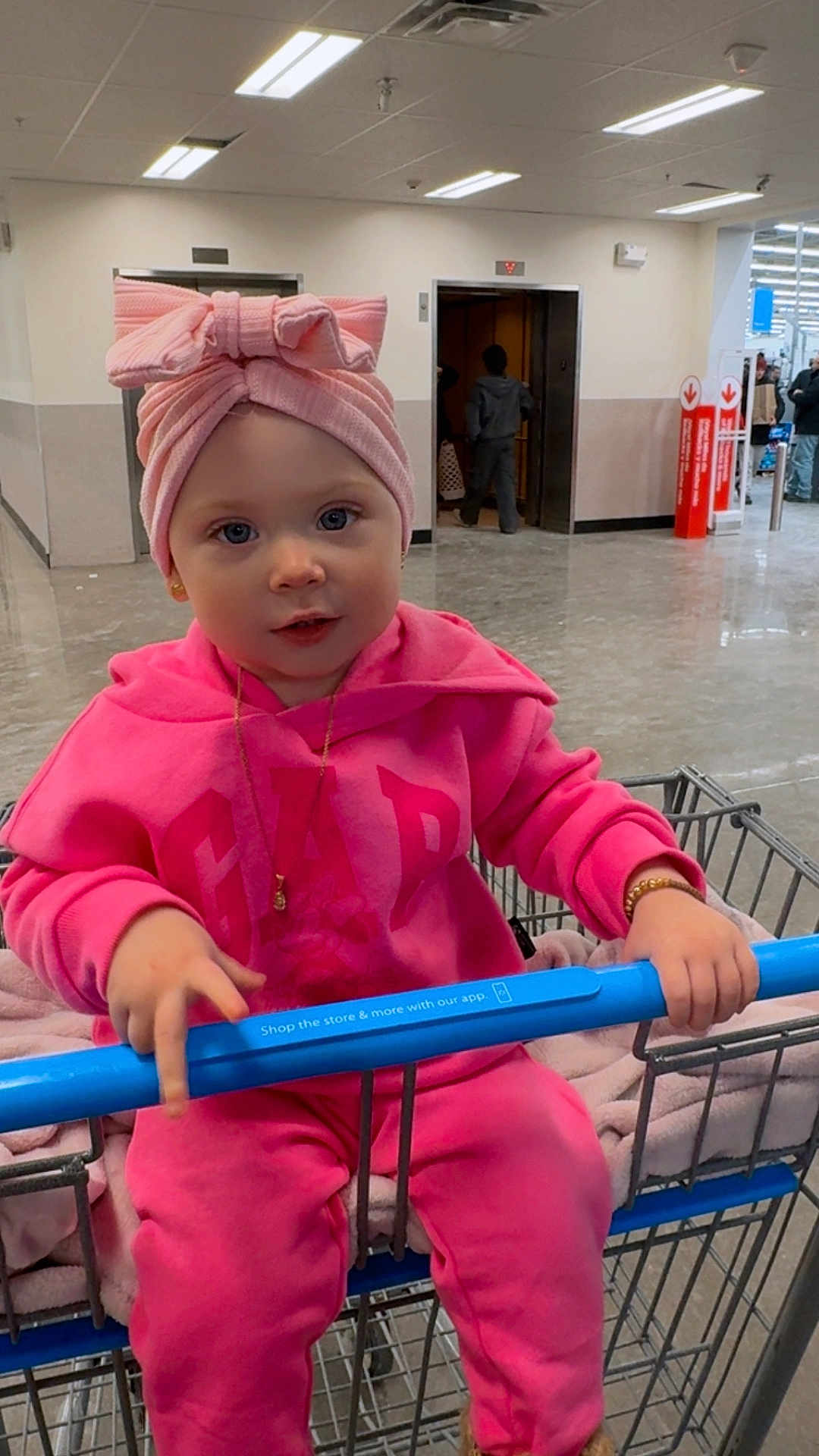 Mariangel joined the competition — help win amazing prizes! toddler, child, shopping_cart, pink_clothing, headwrap, indoor, store, floor, blue_handle, person, jewelry, bracelet, necklace, expression, curious, clothing, retail, floor_tiles, shopping, casual