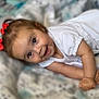baby, child, smiling, happy, face, eyes, hair, bows, white_clothing, blanket, pattern, infant, lying_down, cute, skin, arm, hands, indoors, portrait, young