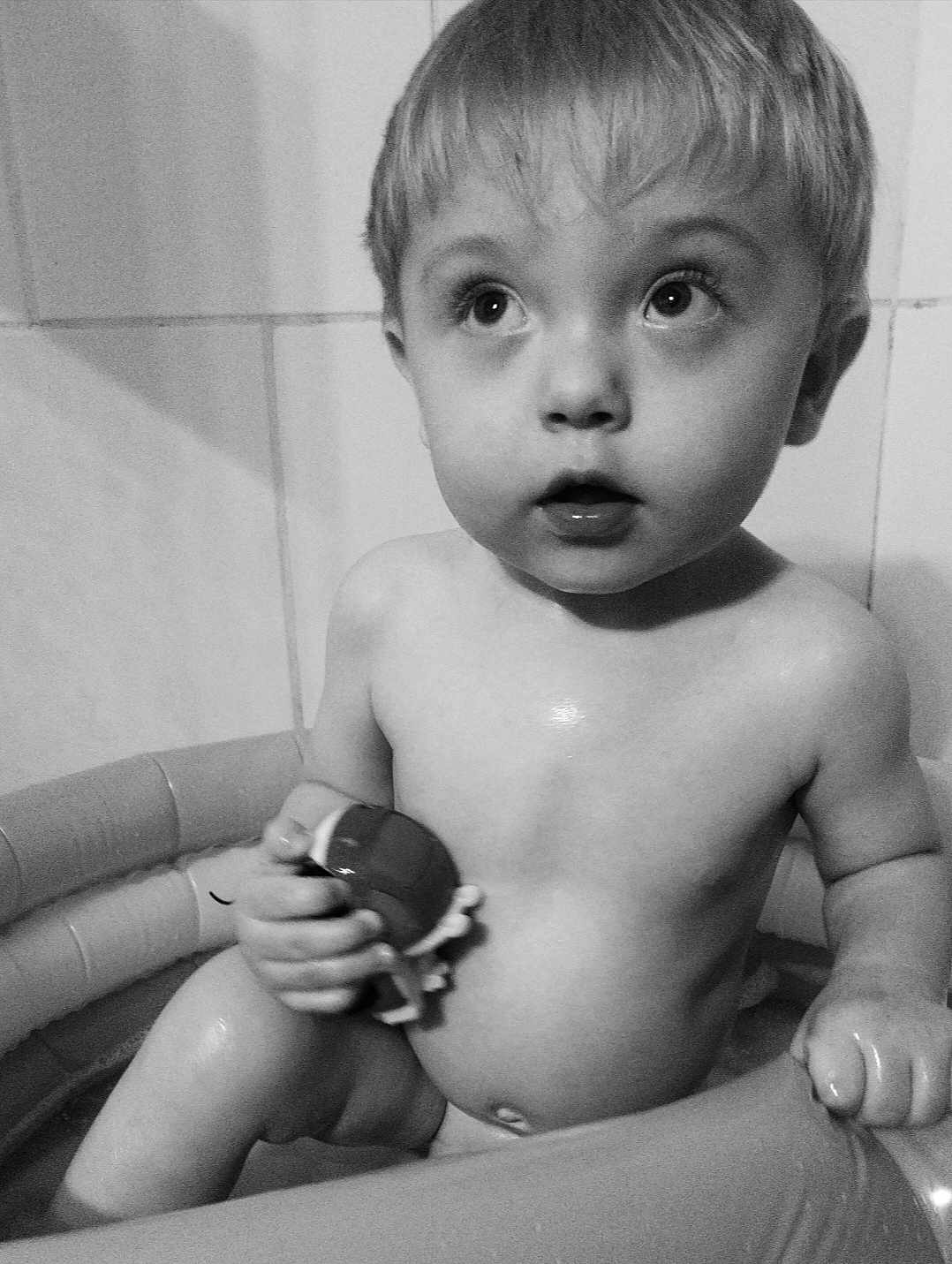 Olan a rejoint le concours — aidez-le/la à gagner de superbes lots ! child, toddler, bath, toy, inflatable_tub, water, naked, skin, face, eyes, hand, curious, expression, indoor, tile_wall, monochrome, black_and_white, bathroom, young, cute