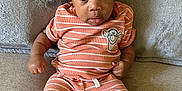 Joshua joined the competition — help win amazing prizes! baby, infant, child, couch, clothing, striped_outfit, socks, face, curly_hair, expression, indoor, portrait, cute, small_hands, seated, soft_texture, cartoon_patch, orange, white, cozy