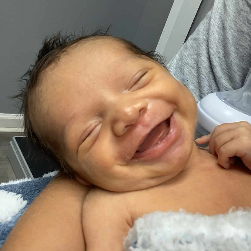 Raul is registered to the contest to win money with this photo: arm, baby, blanket, child, closeup, comfort, cozy, expression, face, happy, human, indoors, infant, newborn, person, portrait, resting, skin, smiling, tattoo