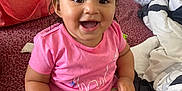 Xiomara is registered to the contest to win money with this photo: toddler, child, smiling, hairbrush, pink_clothing, pigtails, hair_clip, carpet, indoor, crib, blanket, bag, furniture, happy, sitting, person, cute, playful, room, casual