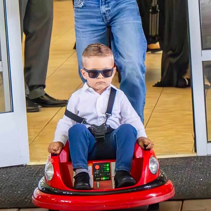 Noah joined the competition — help win amazing prizes! child, toddler, toy_car, sunglasses, adult, remote_control, white_shirt, blue_jeans, indoor, flooring, wooden_floor, person, cool, serious_face, funny, photography, event, people, casual_clothing, technology