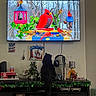 Luna is registered to the contest to win money with this photo: cat, black_cat, television, bird_feeder, birds, indoor, cabinet, decorations, gaming_console, headphones, christmas_decor, wall_art, small_tree, ornaments, living_room, curious, pet, furniture, electronics, holiday