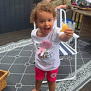 Willow-Rose joined the competition — help win amazing prizes! child, toddler, curly_hair, barefoot, outdoor, rug, chair, woman, smiling, fence, hot_tub, wicker_furniture, table, snack, pink_clothing, white_shirt, garden, daylight, happy, family