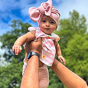 Amelia joined the competition — help win amazing prizes! baby, child, pink_bow, headwrap, floral_top, hands, adult, outdoor, blue_sky, greenery, watch, portrait, cute, smile, person, nature, daylight, holding, happy, infant