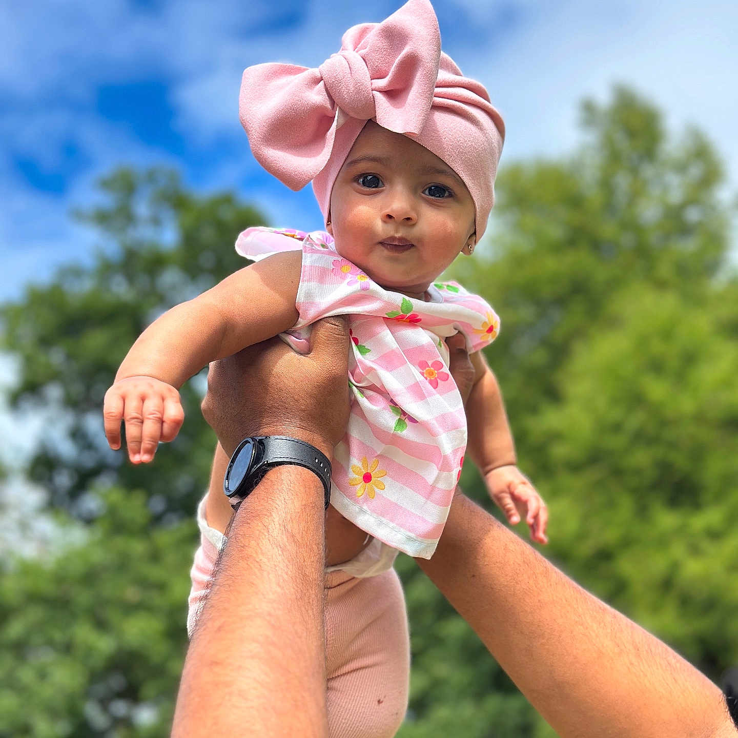 Amelia joined the competition — help win amazing prizes! adult, baby, blue_sky, child, cute, daylight, floral_top, greenery, hands, happy, headwrap, holding, infant, nature, outdoor, person, pink_bow, portrait, smile, watch