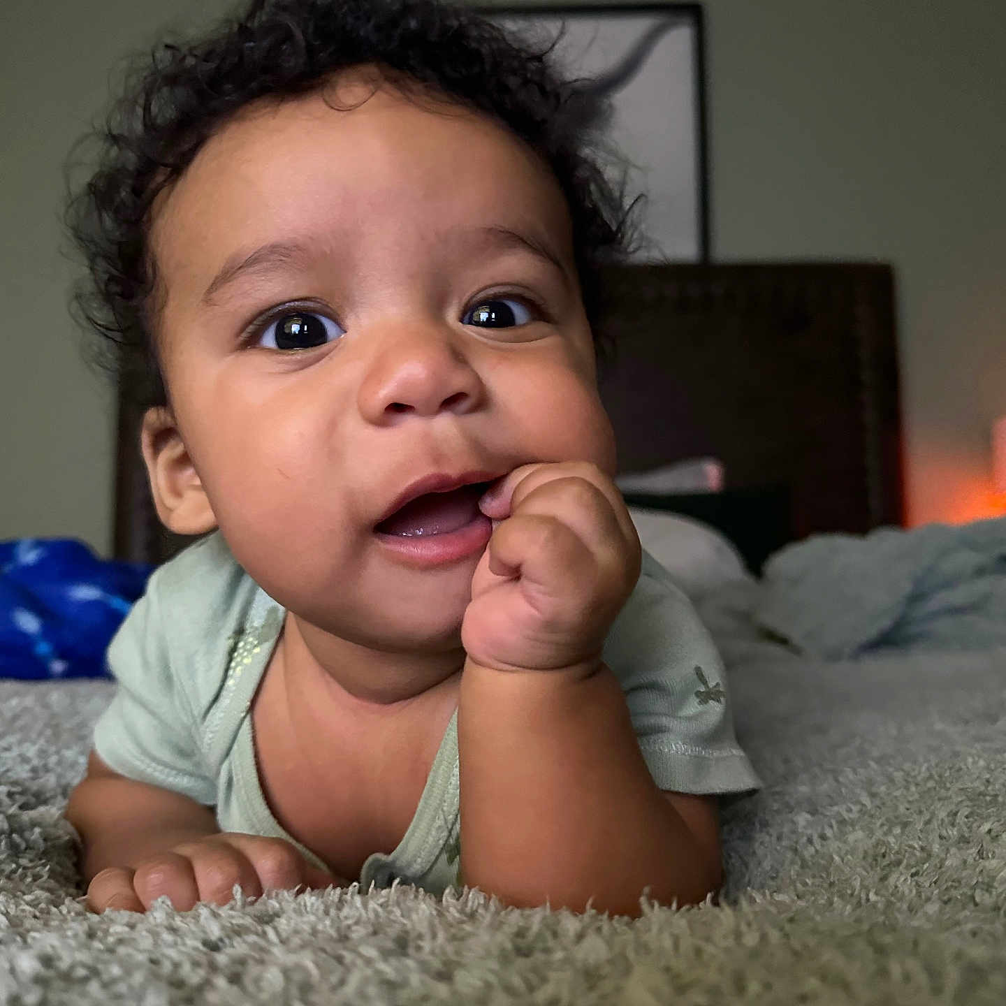Oliver is registered to the contest to win money with this photo: baby, bedroom, carpet, child, cozy, curly_hair, cute, expression, face, hand, indoor, infant, lying_down, person, portrait, skin, smiling, soft_light, toddler, young_child